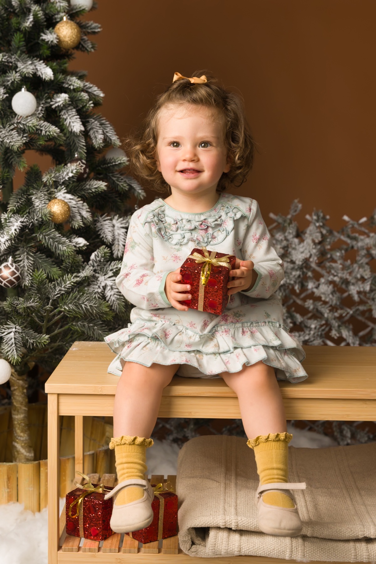 Petite fille assise près d'un sapin de Noël.