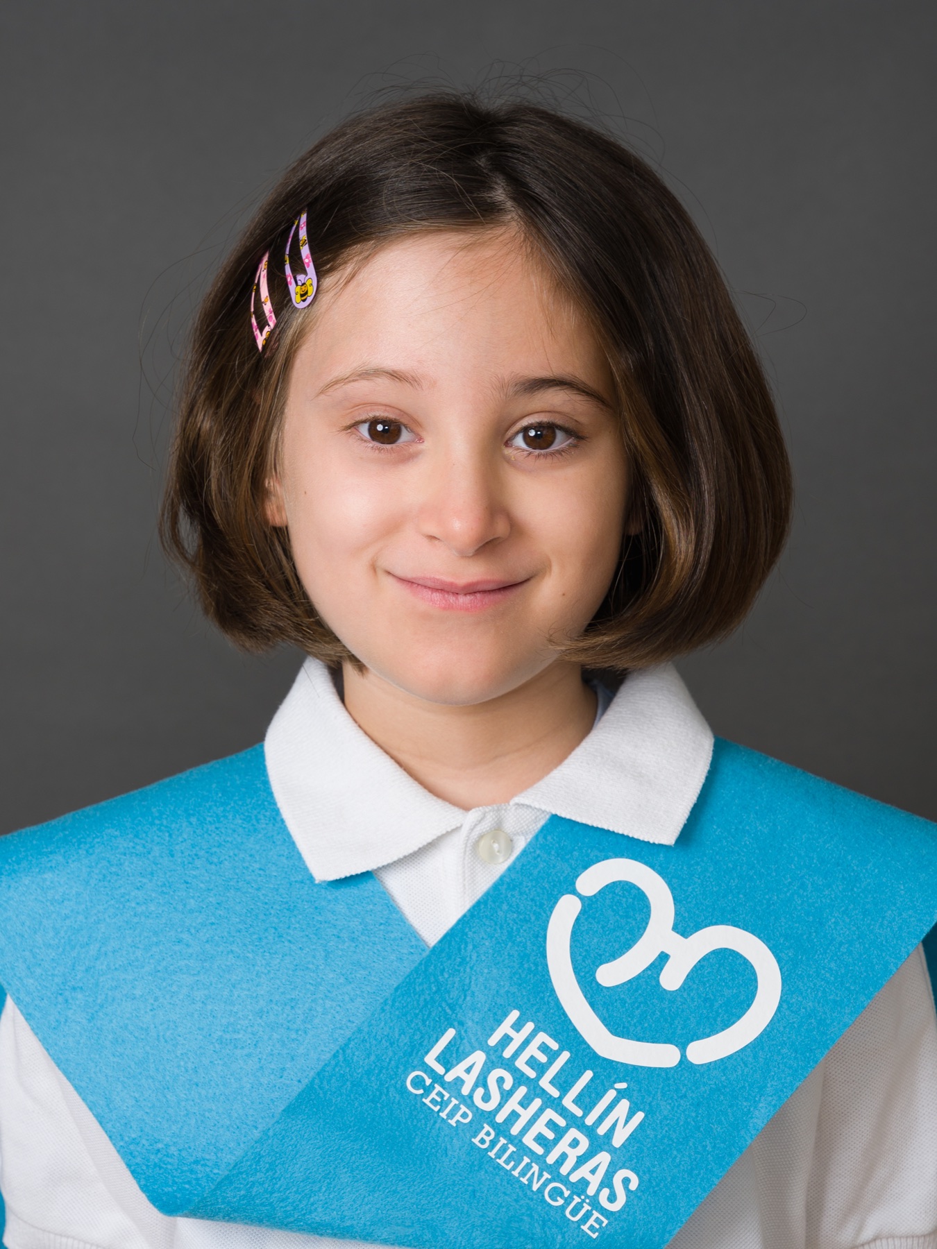 Retrato escolar de una niña con banda de fin de curso.