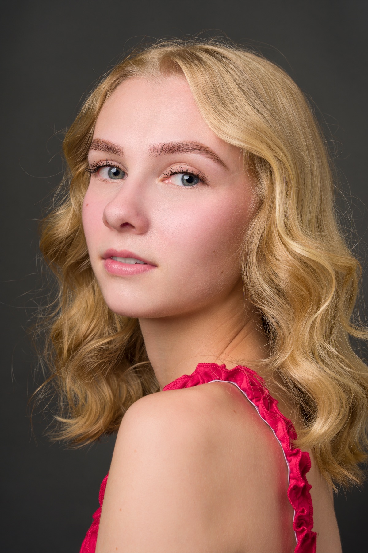 Retrato de casting de una joven rubia sobre fondo oscuro.