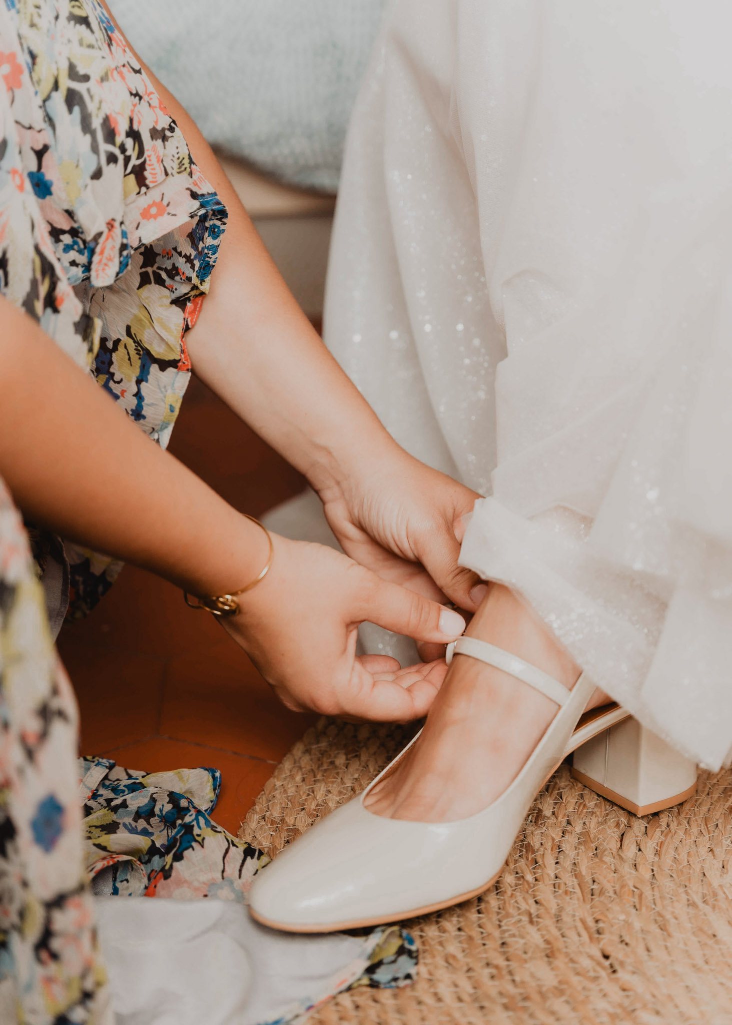 Des mains ajustent la chaussure de la mariée.