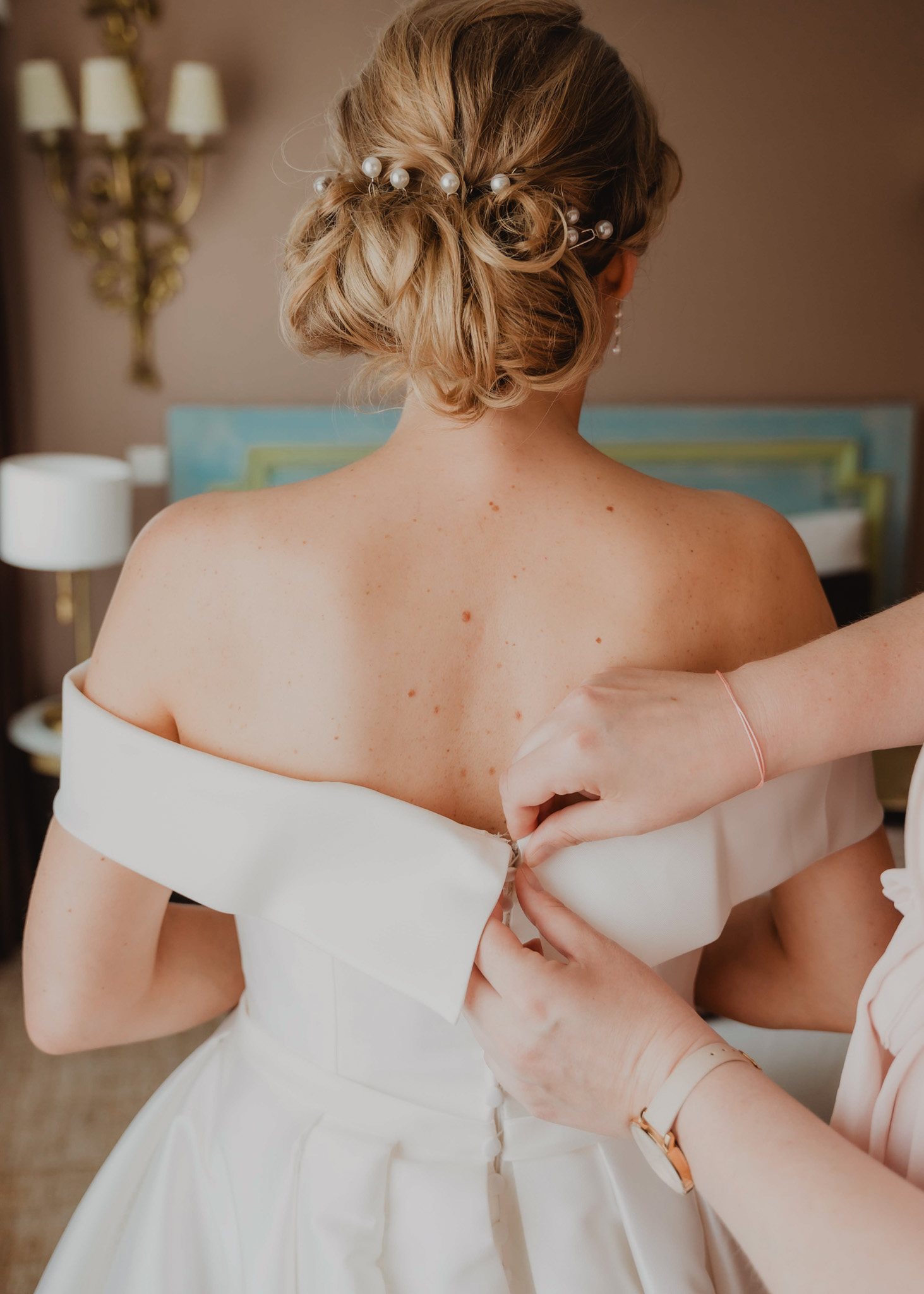 Une proche ajuste la robe de la mariée.