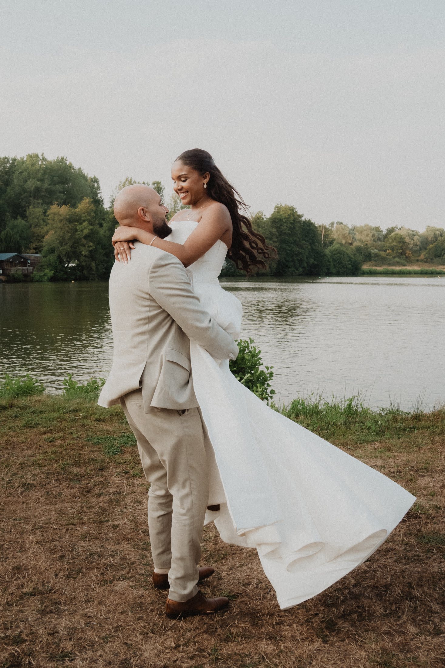 Un marié soulève la mariée près du lac.