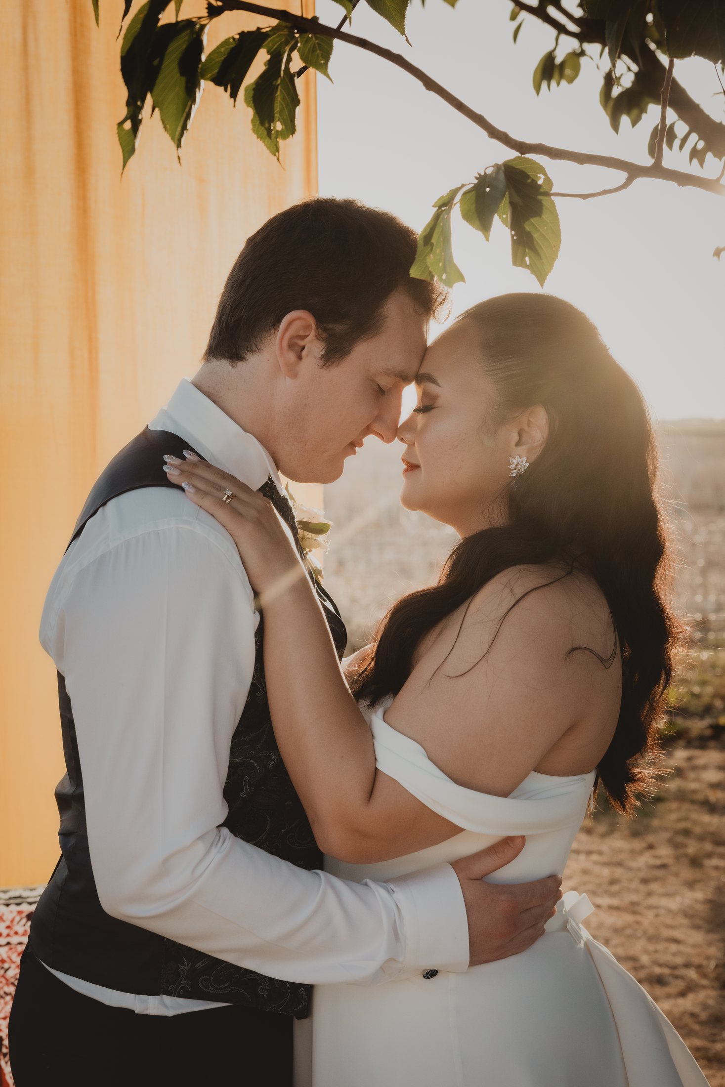 Un couple s'enlace à contre-jour au coucher du soleil.