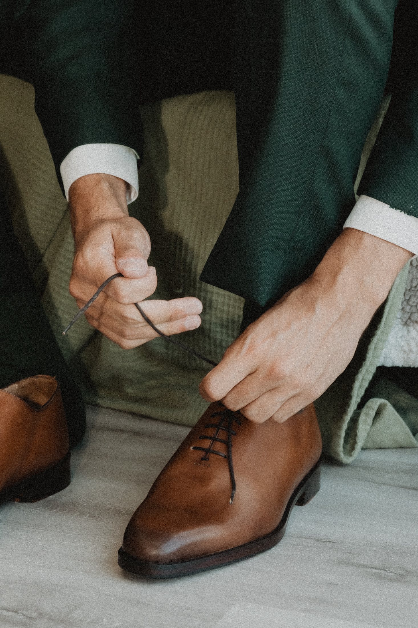 Un marié noue ses chaussures pendant les préparatifs.