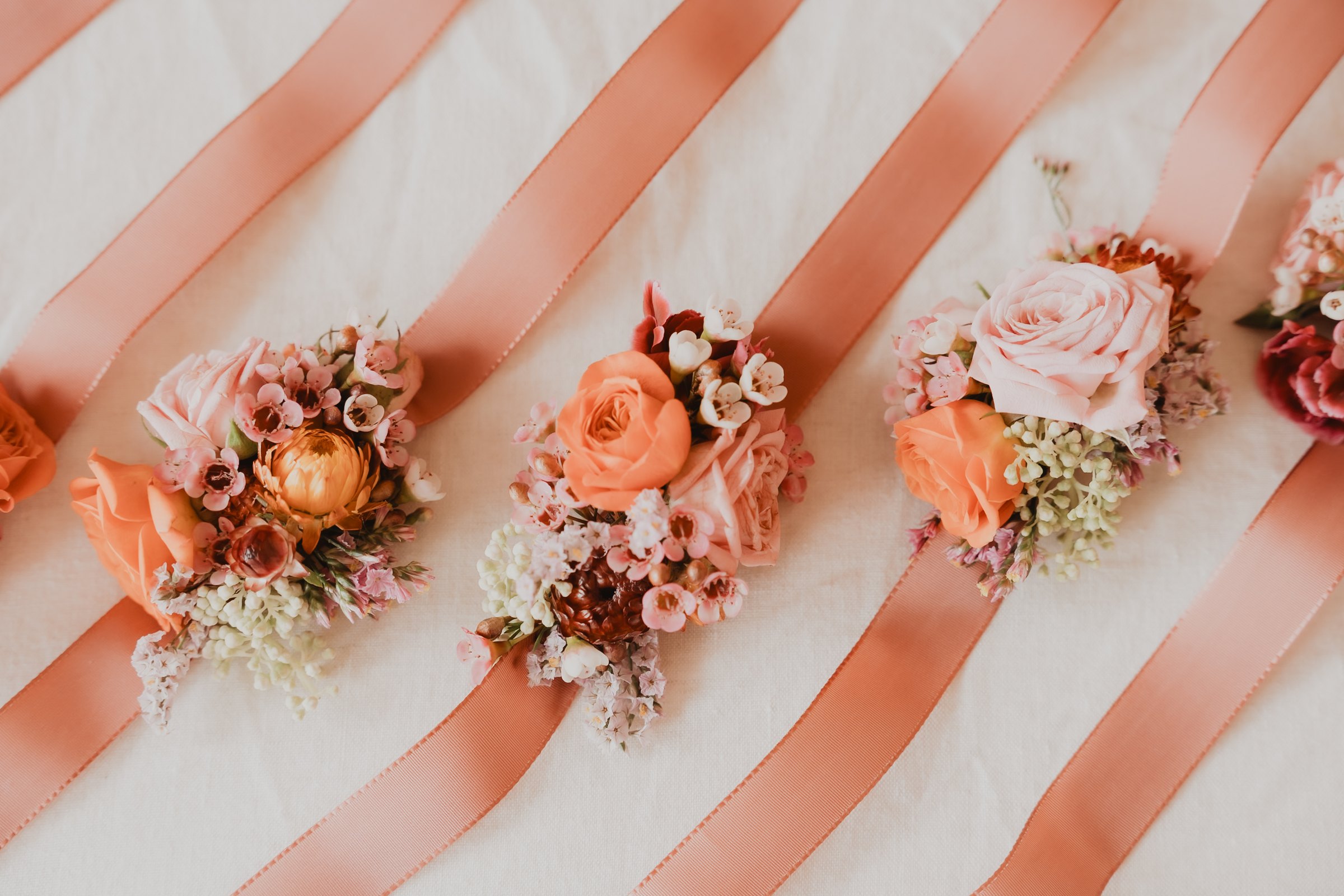 Bouquets de mariage corail disposés sur des rubans.