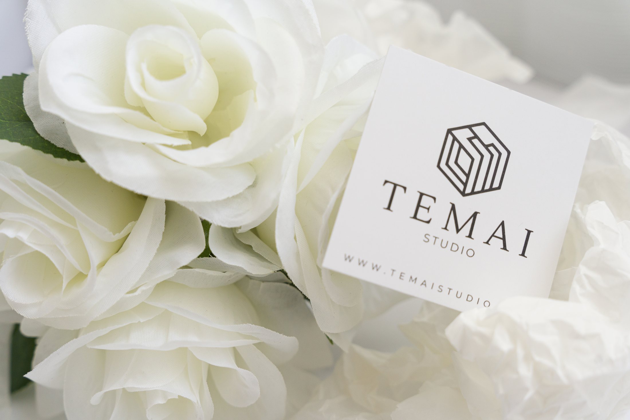 Carte TEMAISTUDIO posée dans des fleurs blanches.