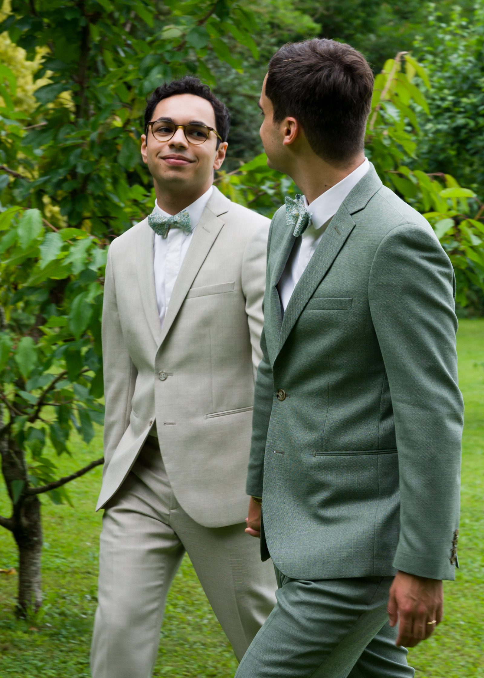 Retrato del novio con traje verde entre las personas invitadas.