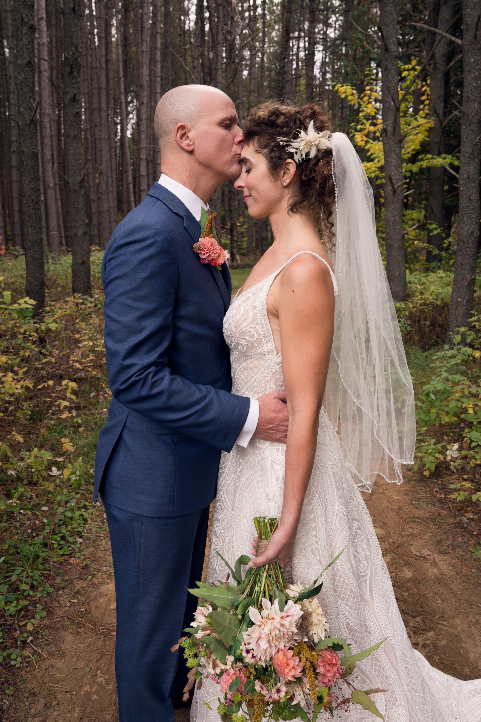 Nadia y Brendan se besan en el bosque de otoño.
