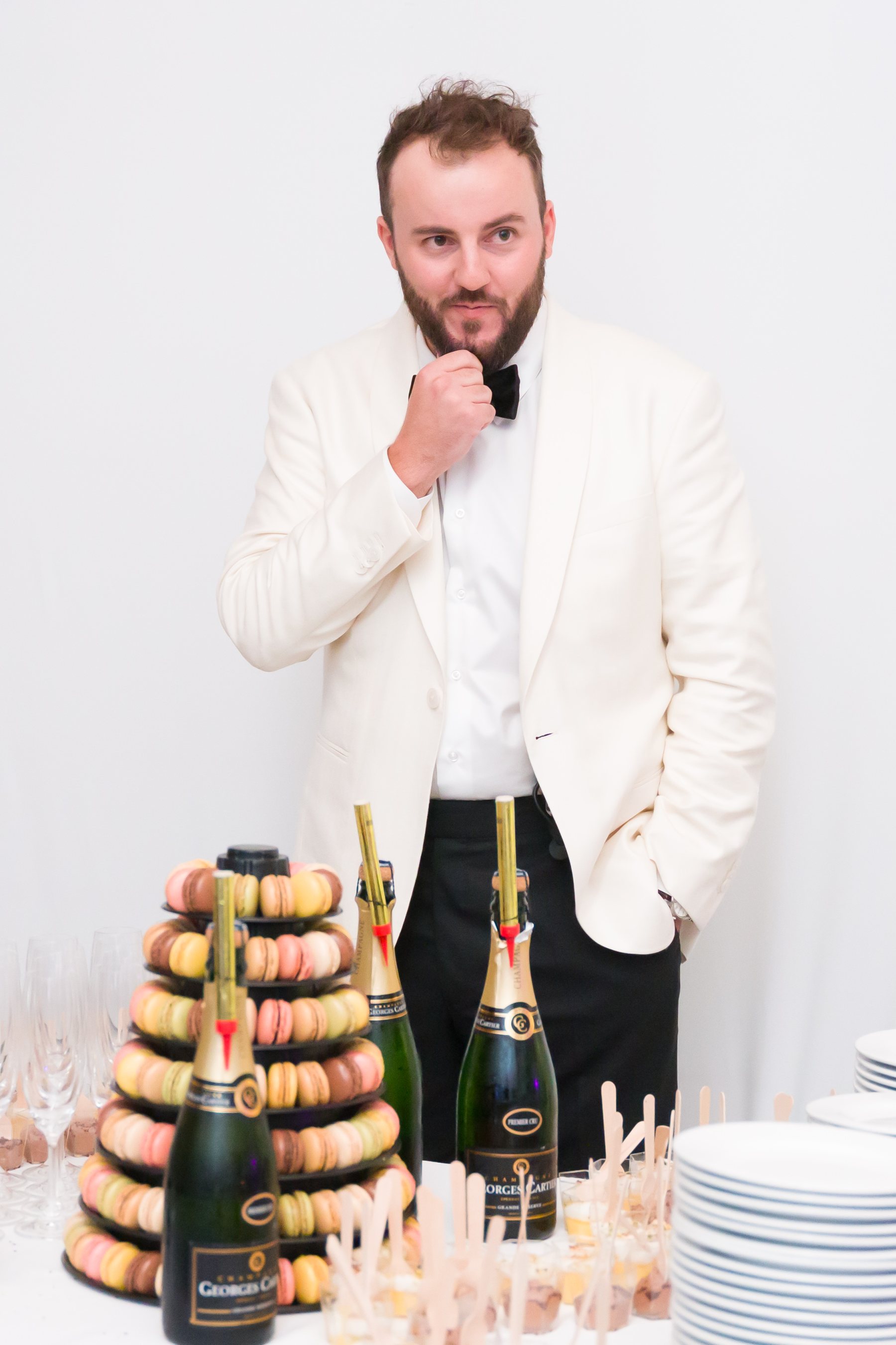 Florian sonríe ante una mesa de recepción y una torre de macarons.